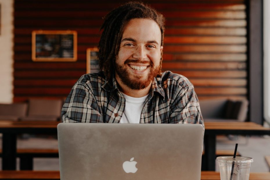 man in black and white striped polo shirt sitting on chair in front of silver macbook